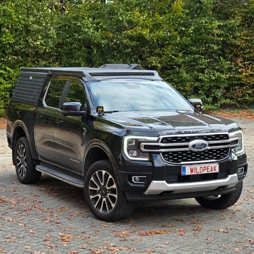Black Ford Wildtrak vehicle parked on a road with trees in the background